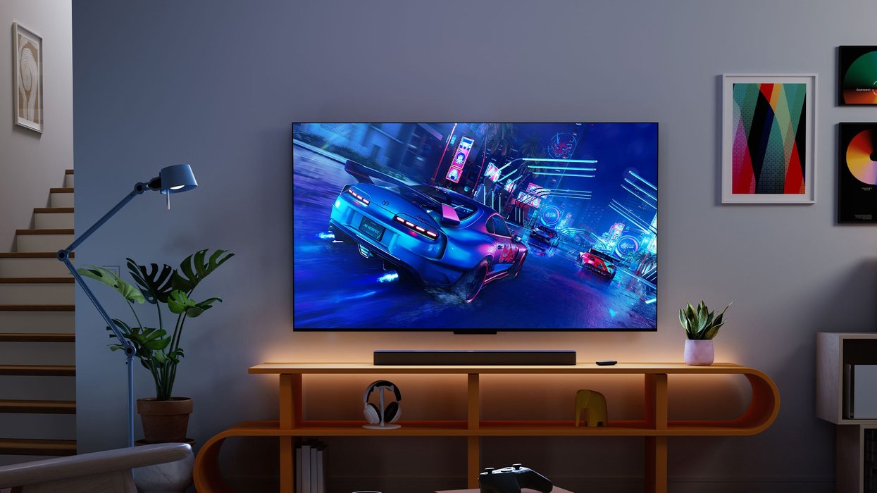 fire tv omni mini-led tv on a media unit with a video game controller pictured on a coffee table
