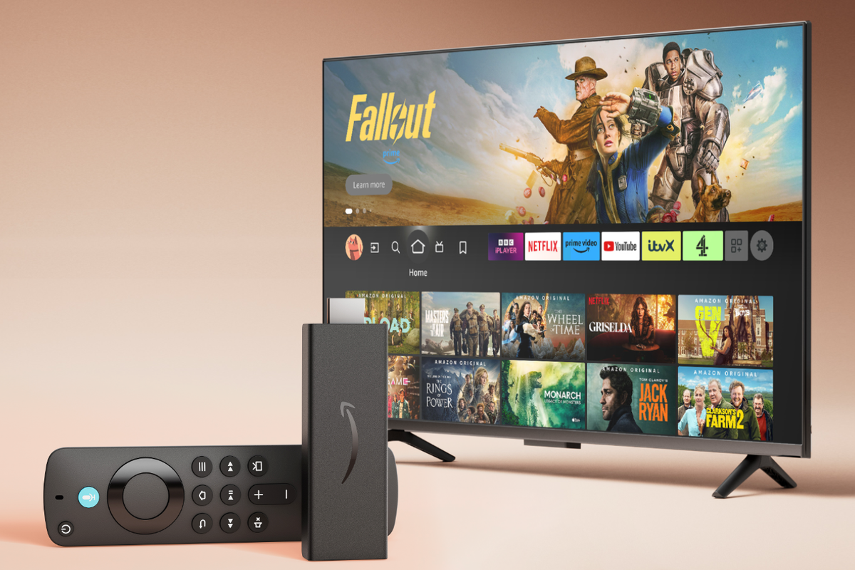 Fire TV Stick HD lying on its side with a television running FireOS in the background