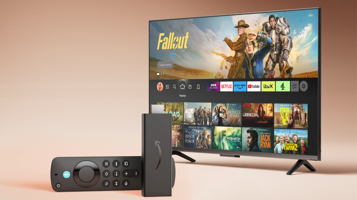 Fire TV Stick HD lying on its side with a television running FireOS in the background