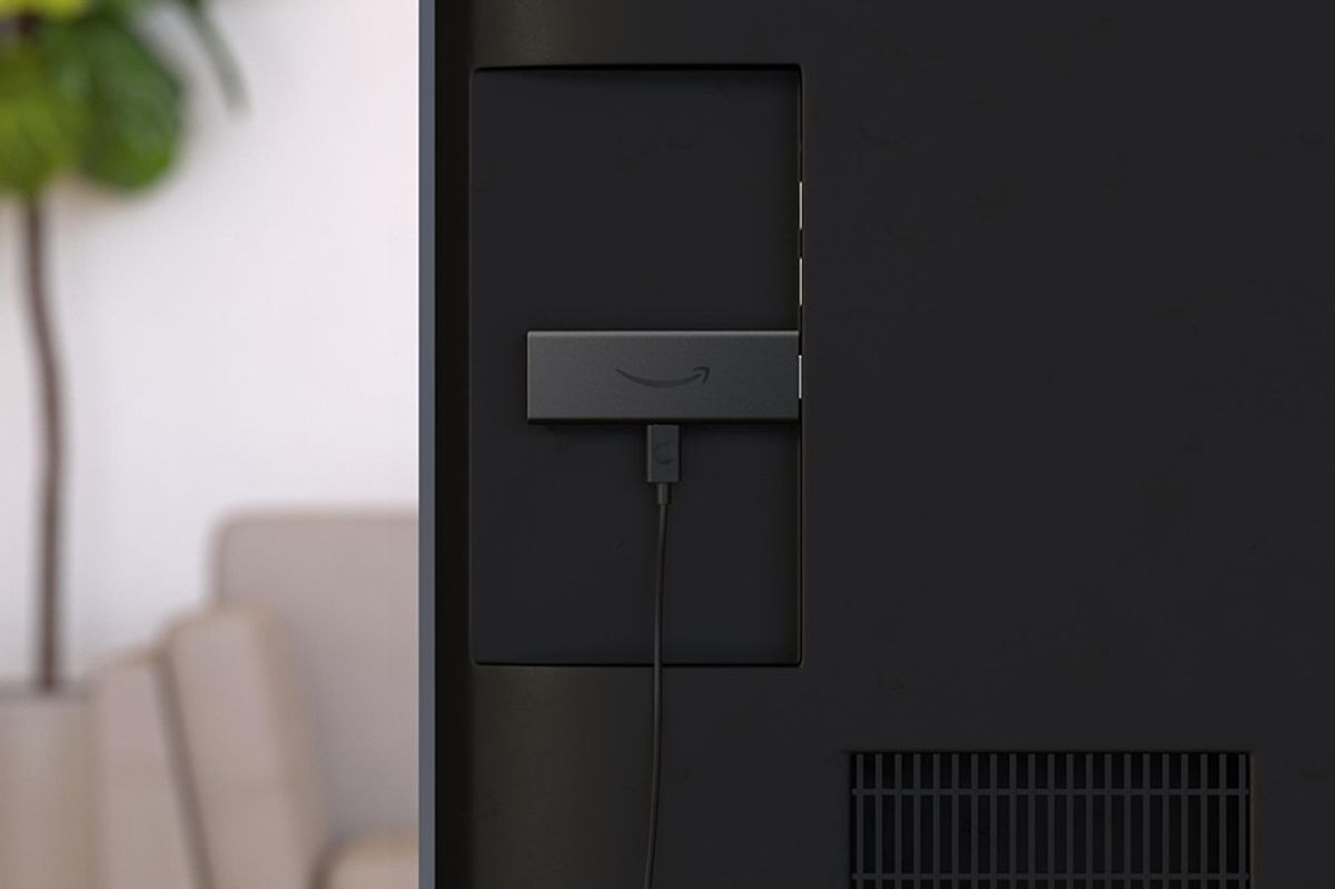 fire tv stick pictured plugged into the back of a flatscreen television