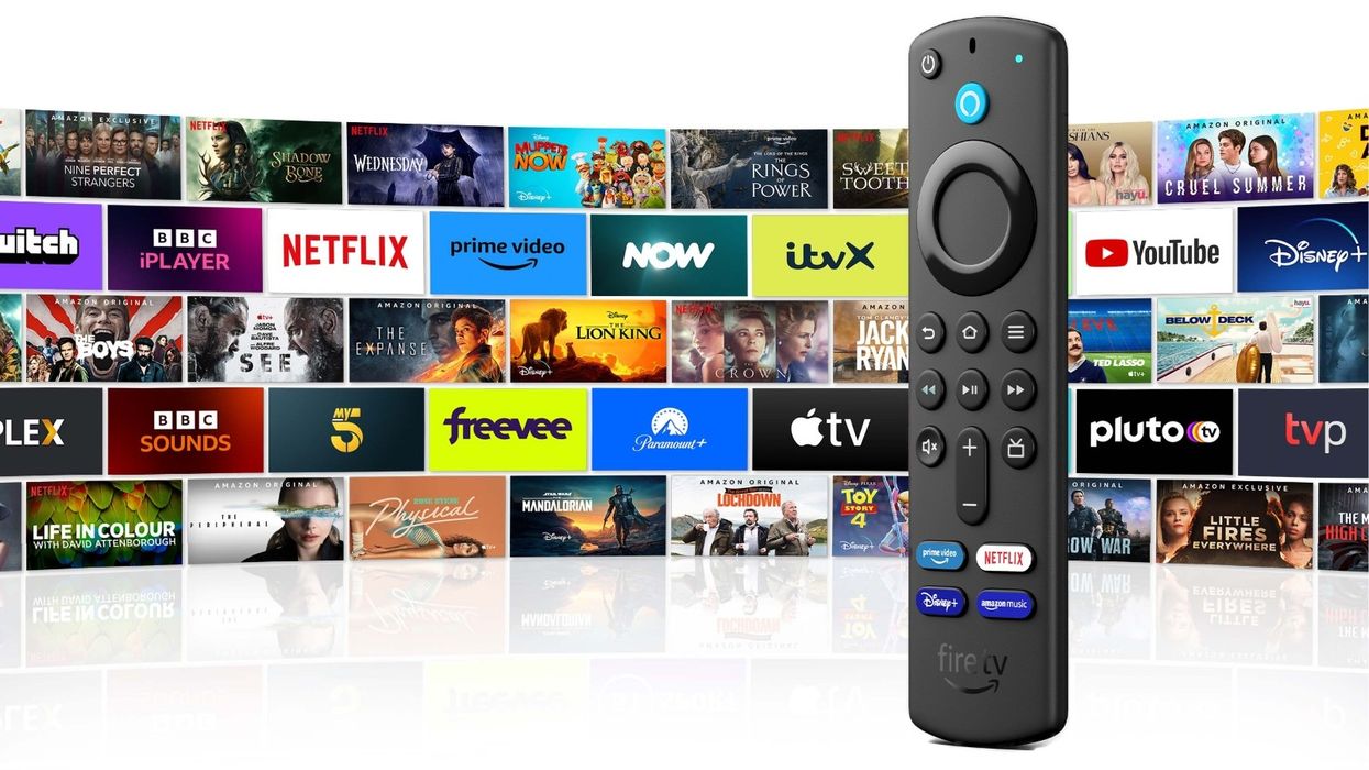 fire tv stick pictured standing with a grid of the apps, streaming services, and games on fireos