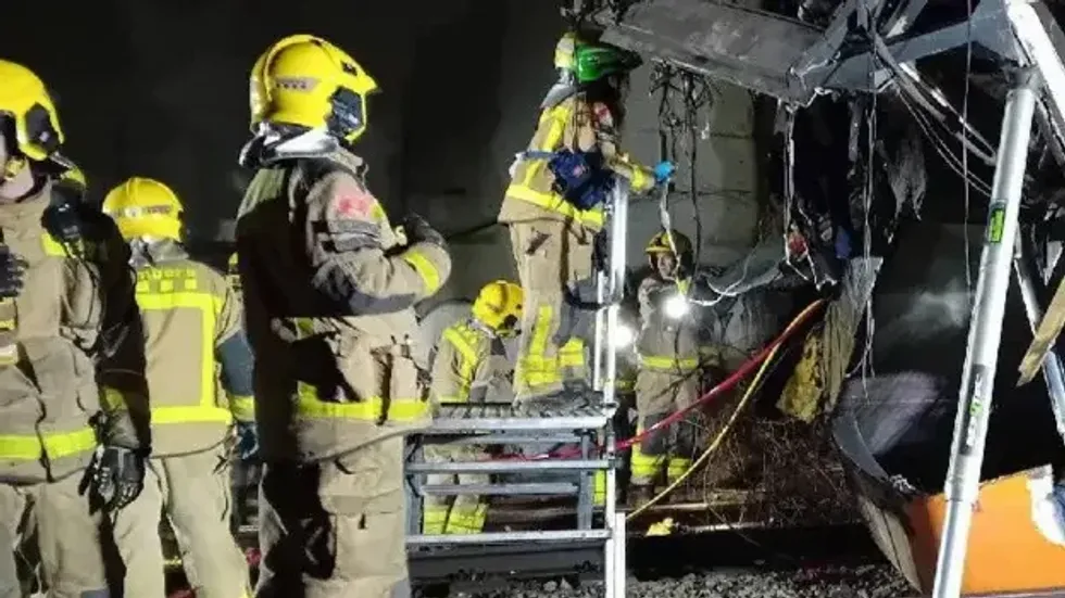 Firefighters examine the wreckage after the deadly derailment
