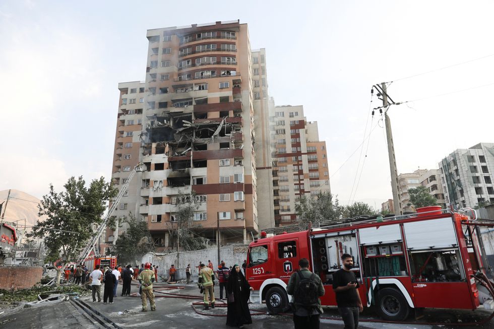 Firefighters scramble to a smouldering tower block in Tehran on the morning of June 13