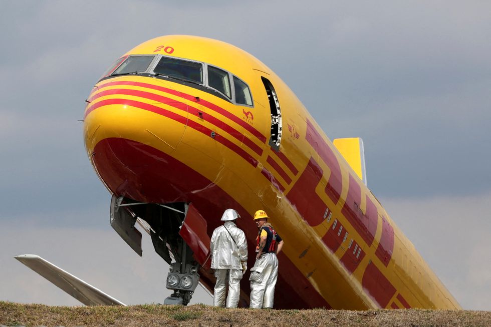 Firefighters stand at the scene where a Boeing 757-200 cargo aircraft operated by DHL made an emergency landing before skidding off the runway and splitting, aviation authorities said, at the Juan Santamaria International Airport in Alajuela, Costa Rica April 7, 2022. REUTERS/Mayela Lopez TPX IMAGES OF THE DAY