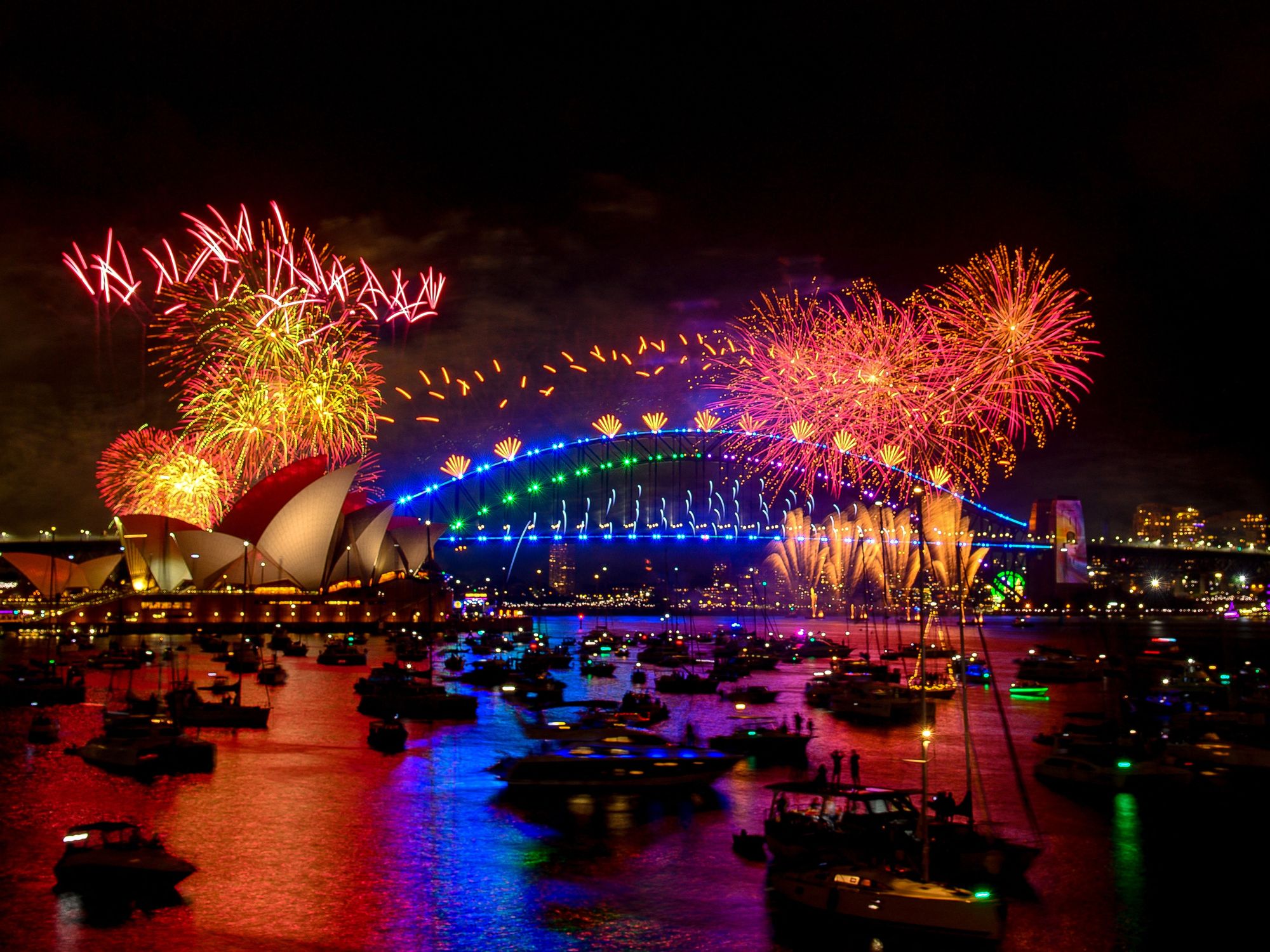 Fireworks explode over the Sydney Harbour Bridge and Sydney Opera House (L) during New Year's Eve celebrations in Sydney on January 1, 2024