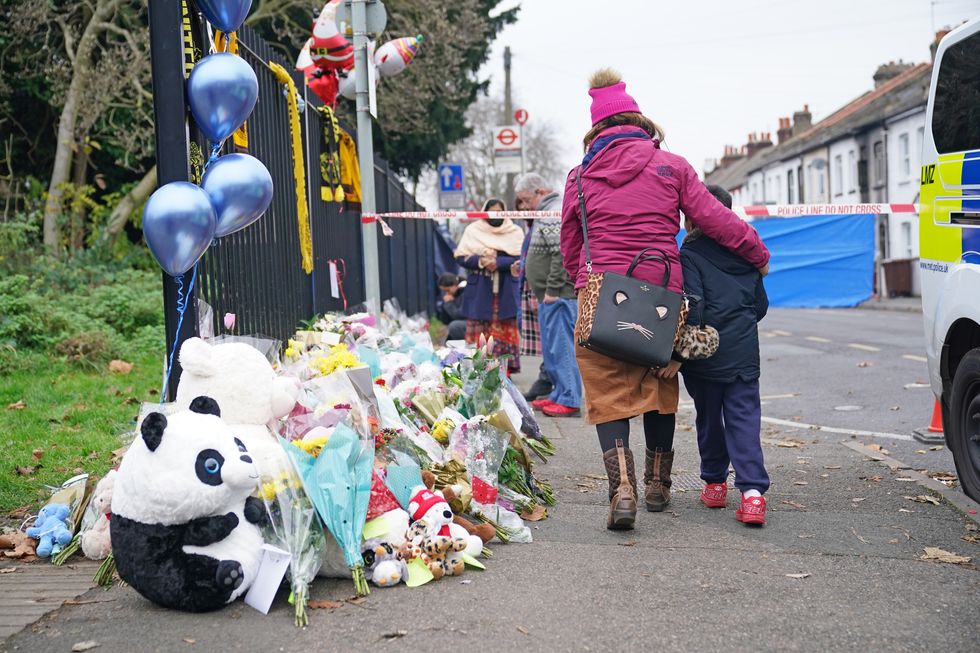 Flowers and toys are left near the scene in Sutton, south London, where two sets of twin boys, aged three and four, died in a devastating house fire on Thursday. A 27-year-old woman has been arrested and held on suspicion of child neglect. Picture date: Saturday December 18, 2021.