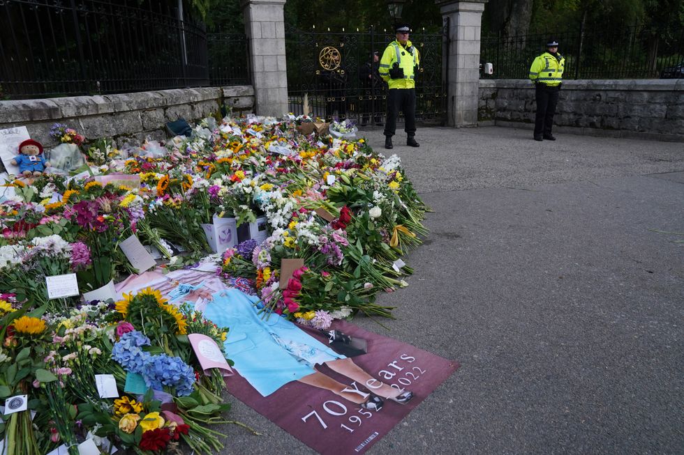 Flowers and tributes laid by members of the public at the gates of Balmoral in Scotland following the death of Queen Elizabeth II. The Queen's coffin will be transported on a six-hour journey from Balmoral to the Palace of Holyroodhouse in Edinburgh, where it will lie at rest. Picture date: Sunday September 11, 2022.