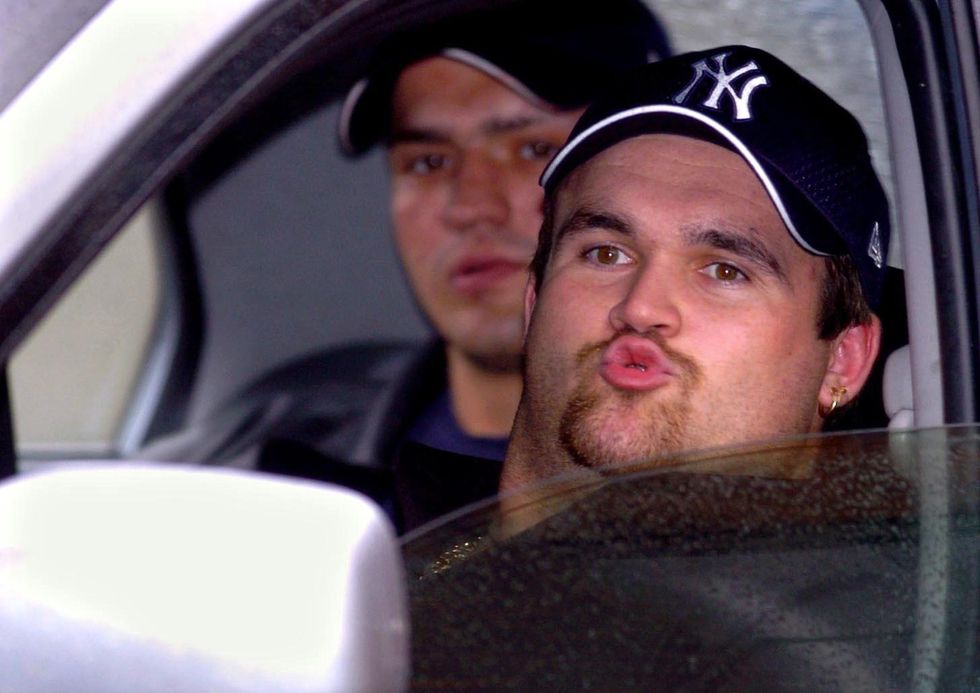 Former dustman turned \u00a39.7 million National Lottery jackpot winner Michael Carroll (right) is driven away after being accused of breaching an Asbo.