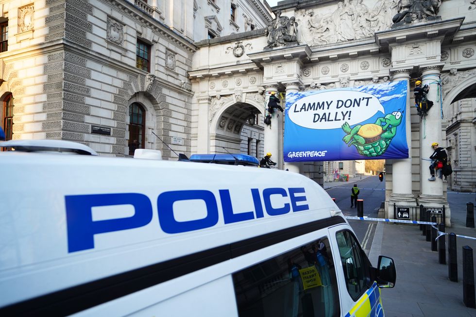Four Greenpeace activists unfurl a banner calling for Foreign Secretary David Lammy to sign the Global Ocean Treaty into UK law