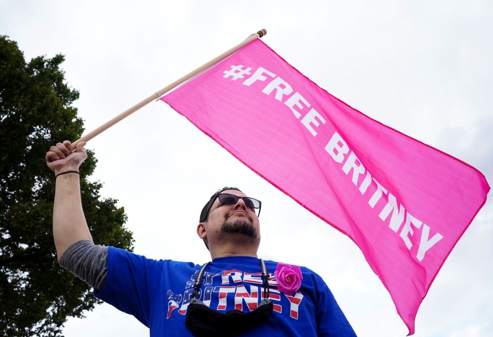 Frankie Ortiz waves a flag as he attends a %22Free Britney%22 demonstration on the Ellipse, near the White House, in Washington, U.S.