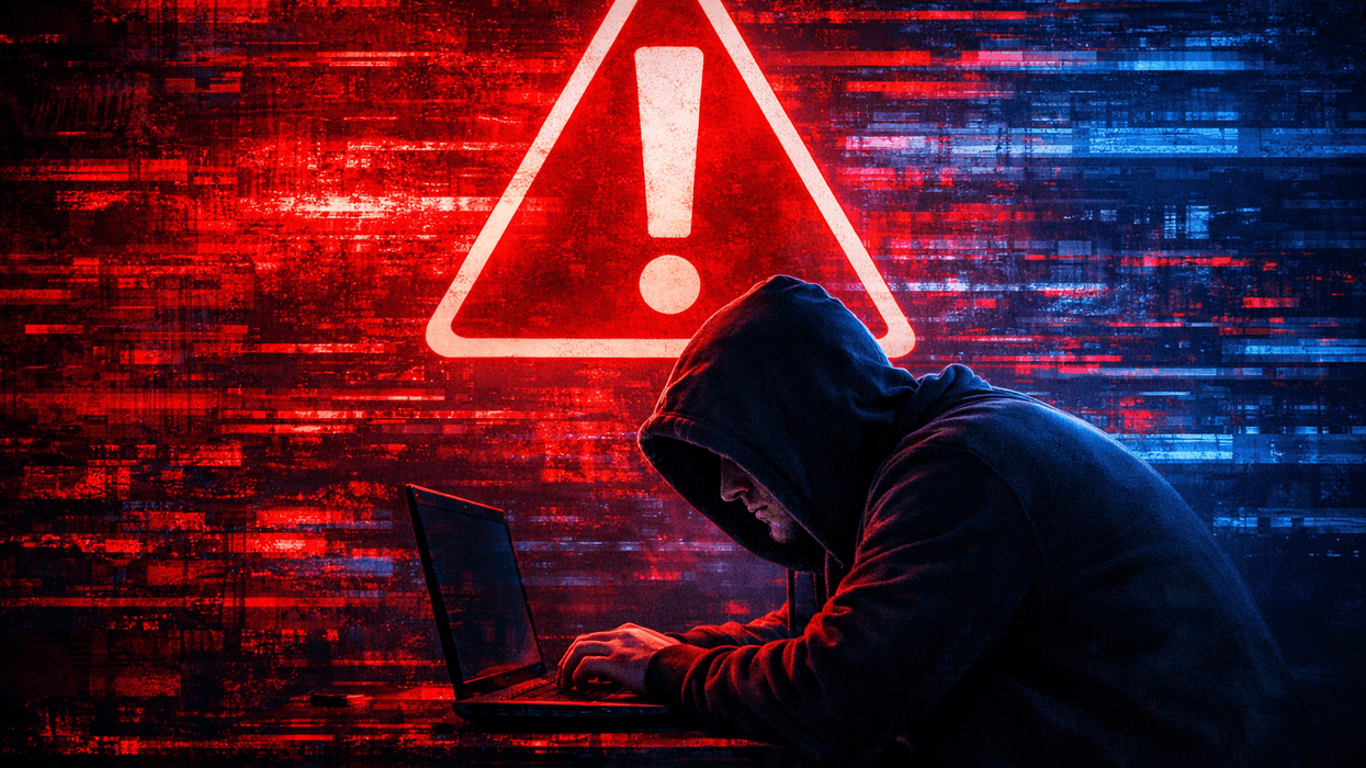 Fraudster with laptop in front of red warning sign