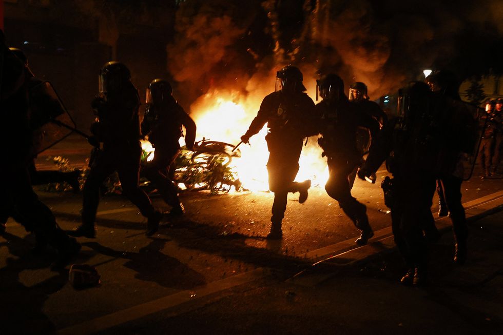 French CRS riot police run past burning bicycles during clashes with demonstrators