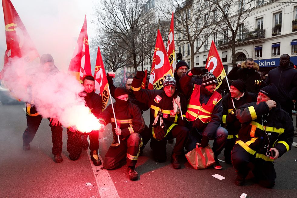 French firefighters on strike holding flares and CGT union flags during the demonstration in France