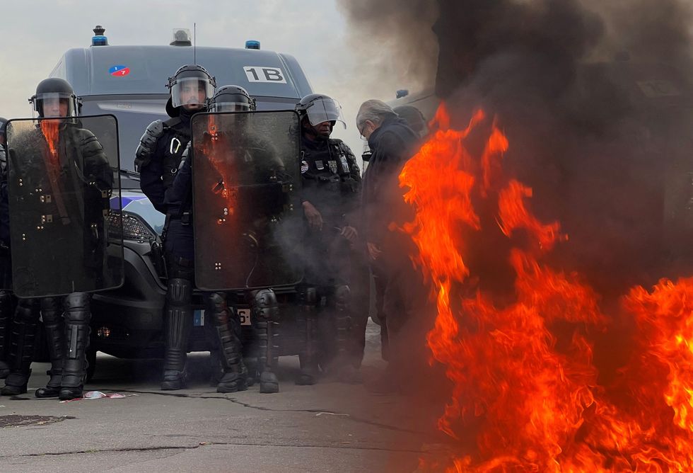 French gendarmes and CRS riot police stand on position near a fire as demonstrators gather on Place de la Concorde