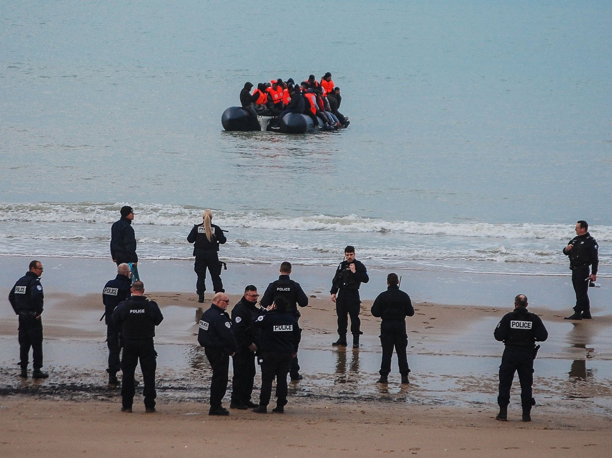French police and small migrant boat at Calais