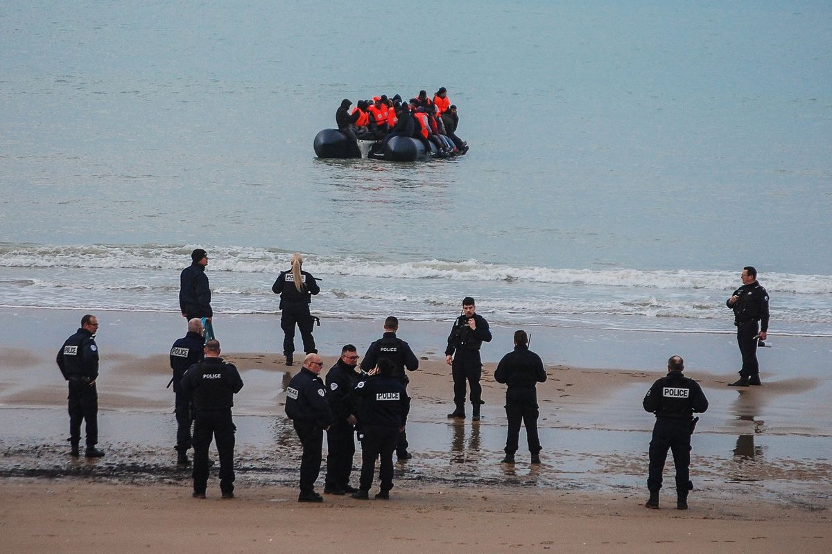 French police and small migrant boat at Calais