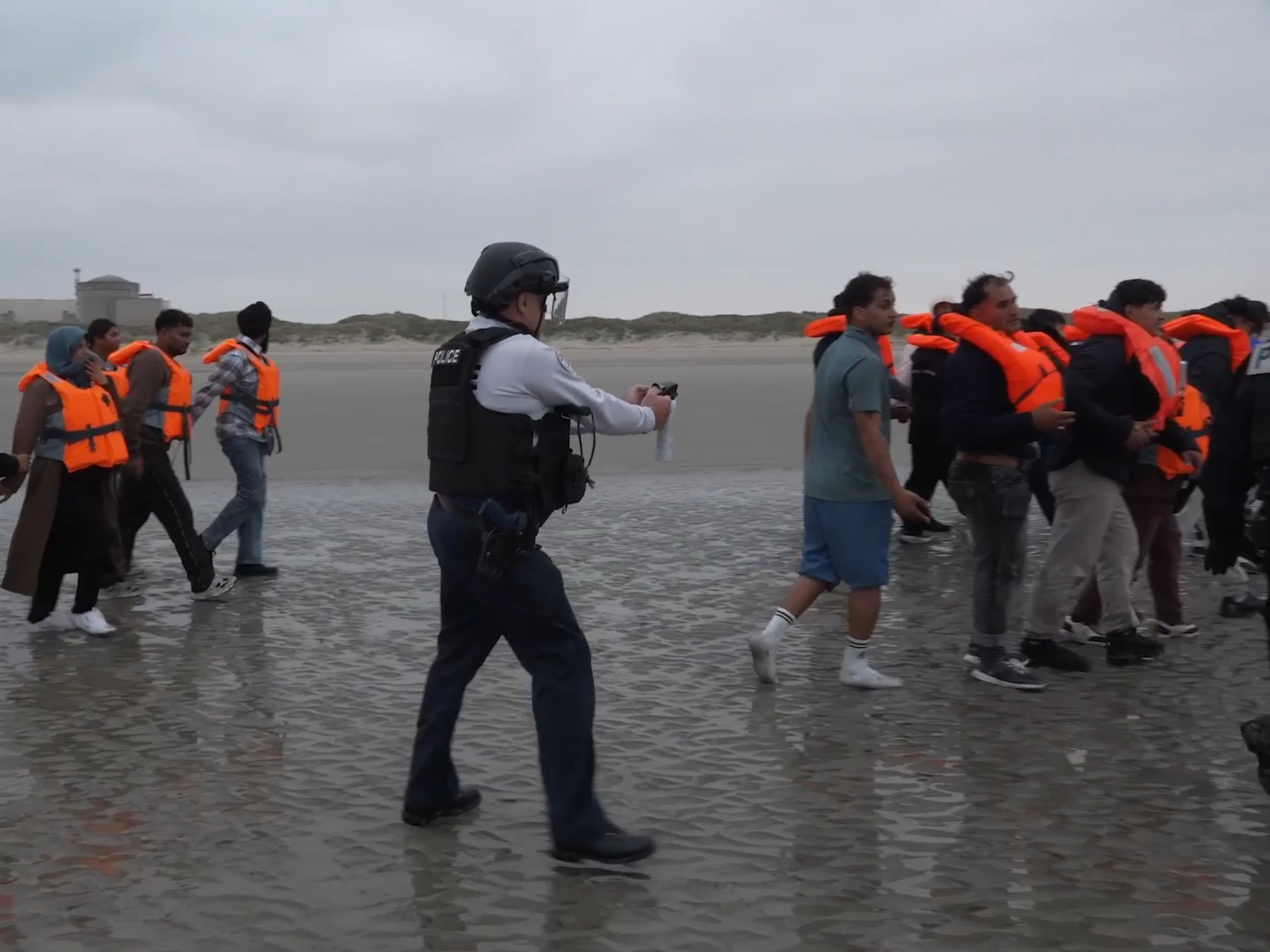 French Police pointing pepper spray at migrants attempting to cross the Channel on small boats
