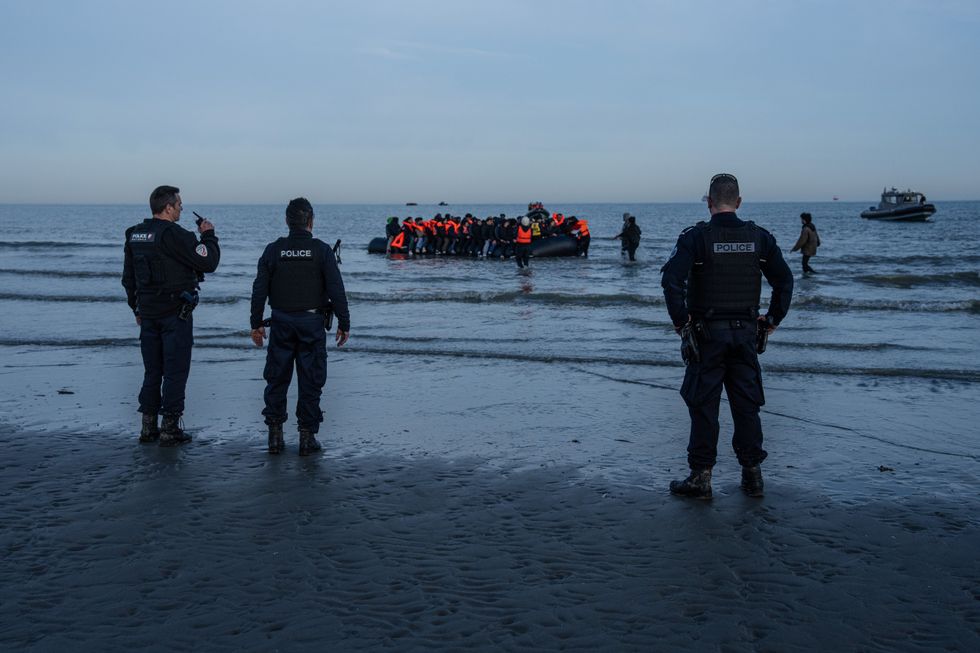 French police watch migrant boat from the beach