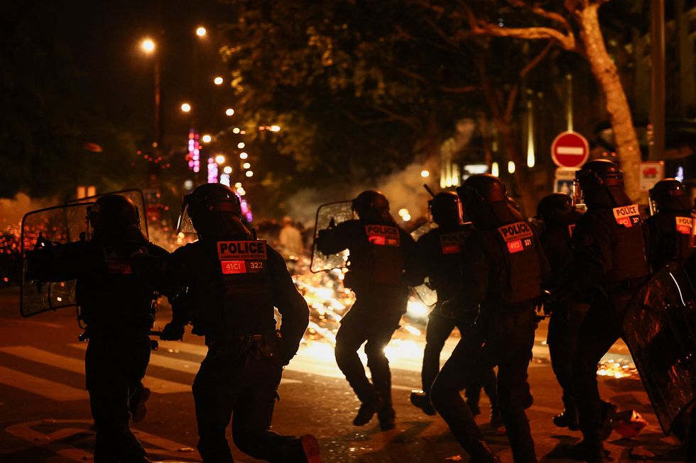 French riot police run during clashes with demonstrators following partial results in the second round of the early French parliamentary elections