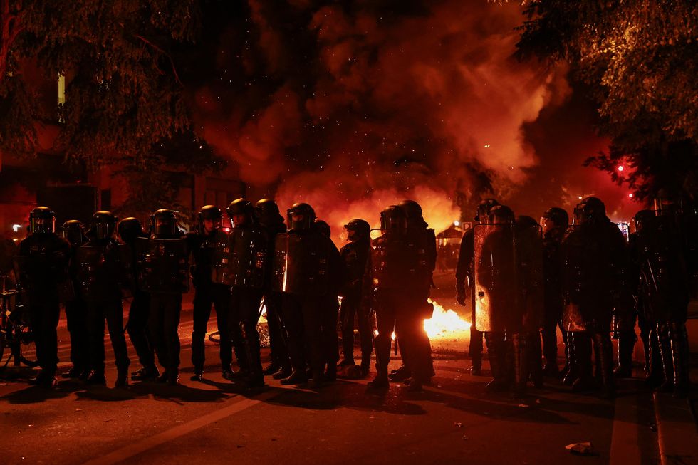 French riot police stand in position near burning bicycles during clashes with demonstrators