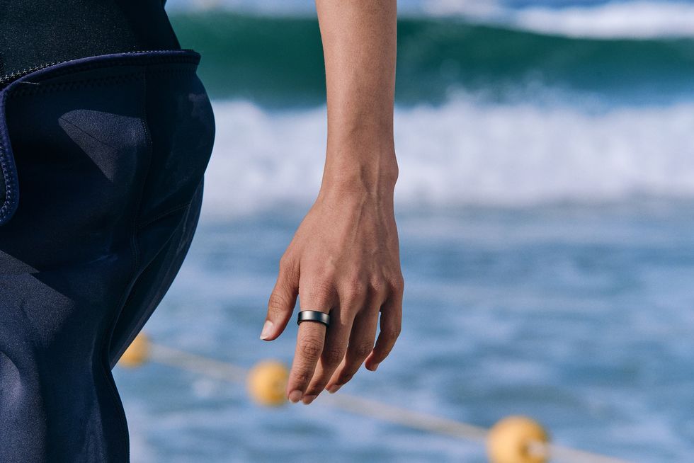 galaxy ring on a hand as they walk along the coast
