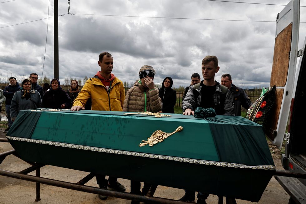 Galyna, 55, mourns her husband, Oleh Tovkach, who according to her was killed by Russian soldiers while trying to escape Bucha, as she stands with her sons Anton, 32, and Roman, 34, during his funeral, amid Russia's invasion of Ukraine, at the cemetery in Bucha, Kyiv region, Ukraine.