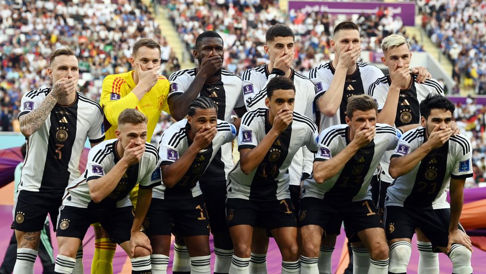 Germany players pose for a team group photo covering their mouths before the match