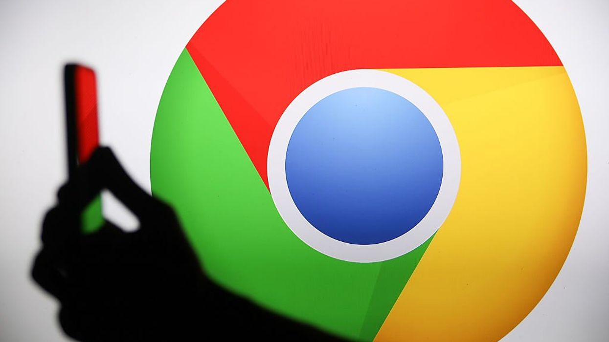 Google Chrome logo behind hand holding phone