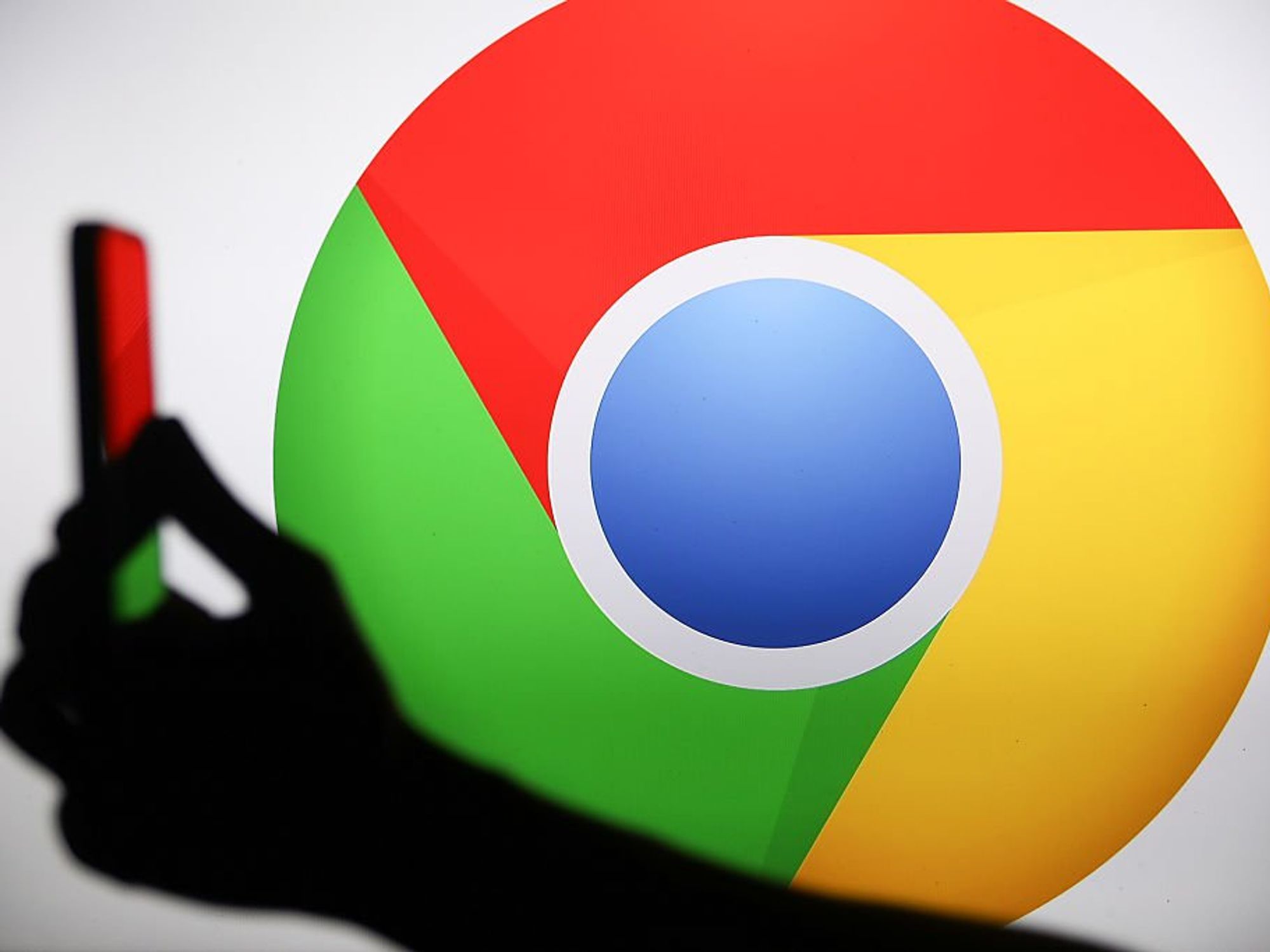 Google Chrome logo behind hand holding phone
