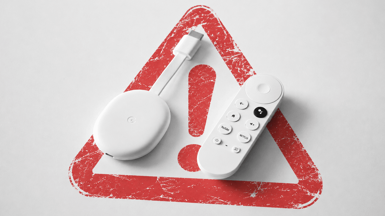 google chromecast shown on a table with a warning triangle in the background