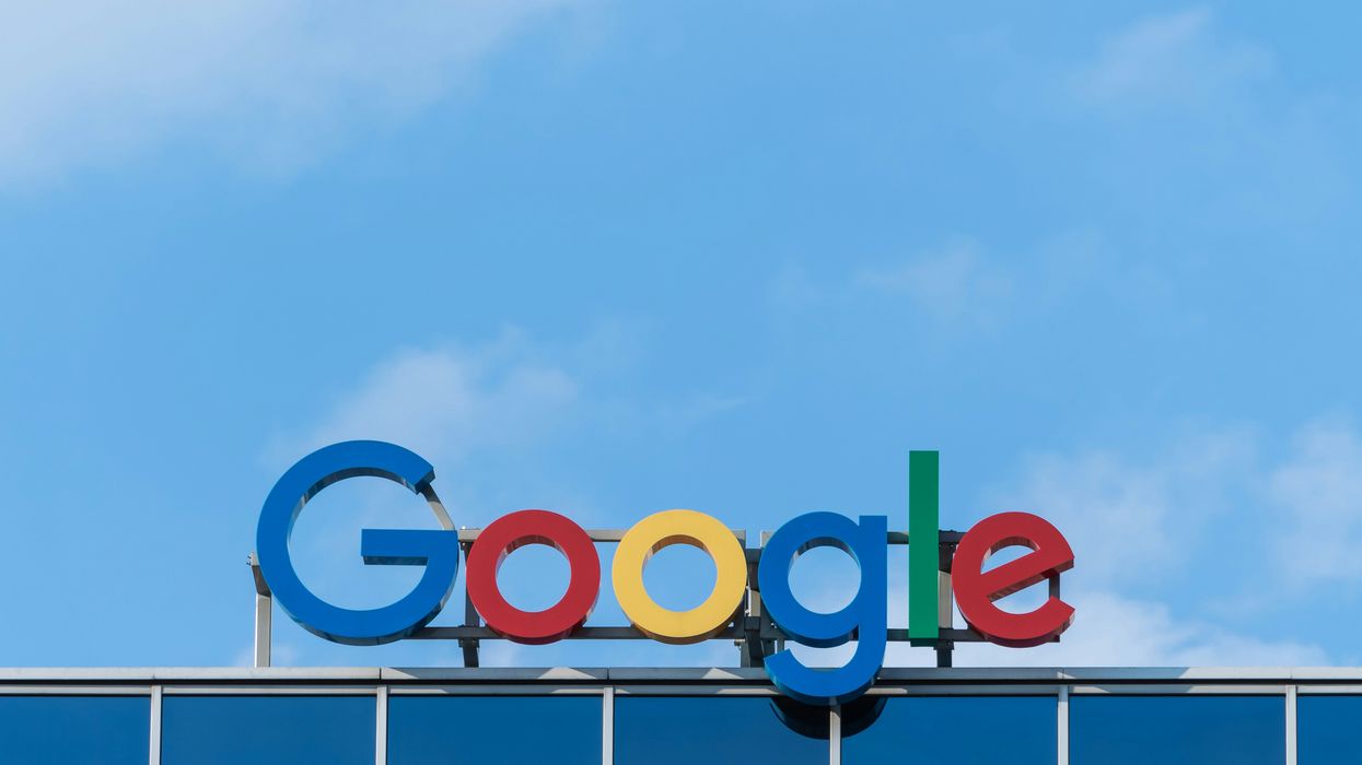 google logo pictured at the top of one of its buildings with a blue sky behind it