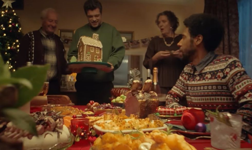 Grandson and grandfather with loved ones around dinner table at Christmas