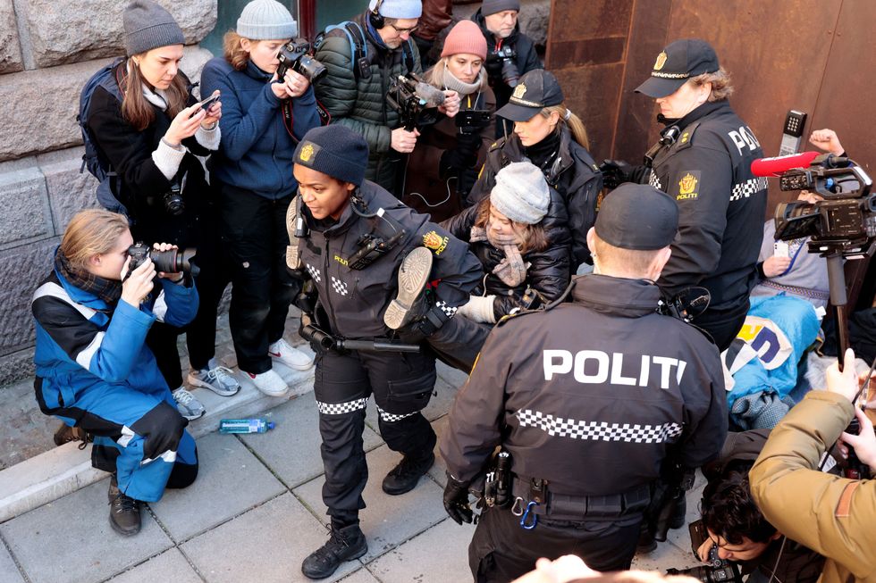 Greta Thunberg is carried away by police officers as activits demonstrate outside the Ministry of Finance entrance