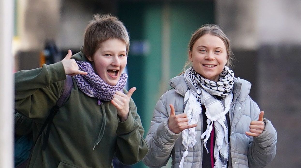 Greta Thunberg poses and smiles in front of the camera while arriving at court over eco-protest