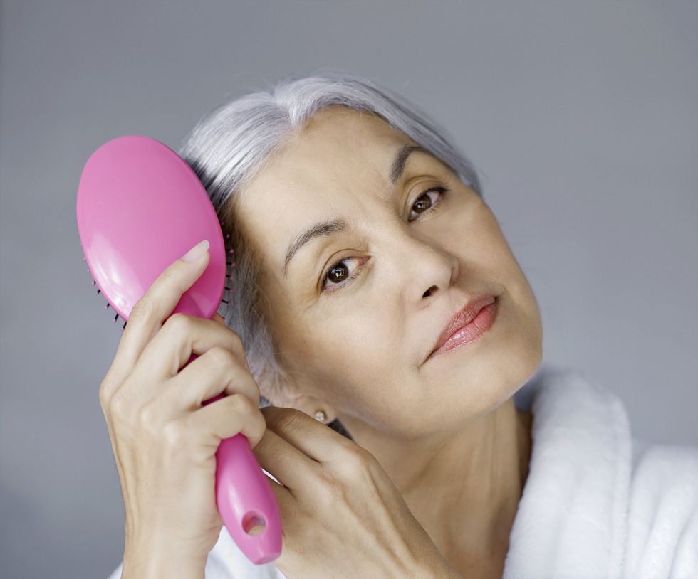 grey-haired woman brushing hair