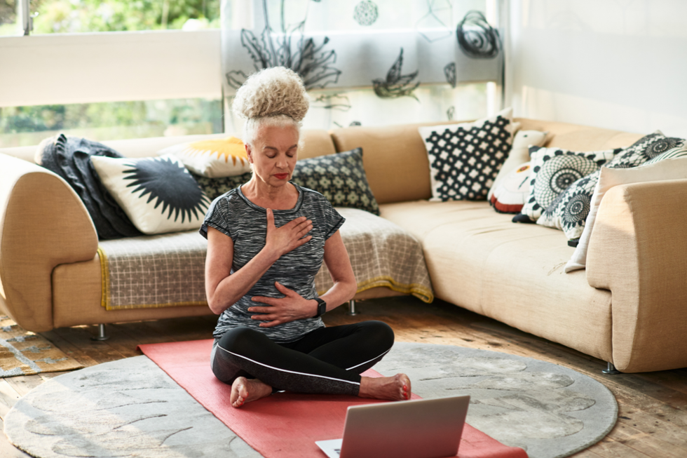 Grey haired woman doing breathing exercises at home