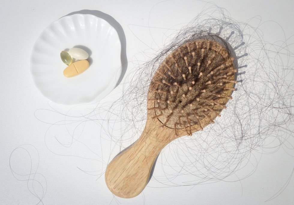 Hair vitamins next to a hair brush covered in hair