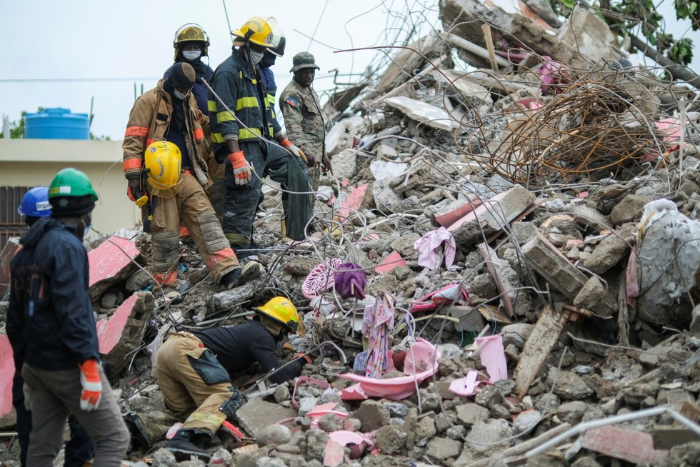 Haitian firefighters search for survivors under the rubble of a destroyed building after Saturday's 7.2 magnitude quake, in Les Cayes, Haiti.