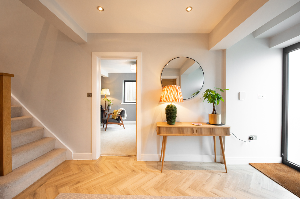Hallway decorated with a lamp, wooden floors, mirror and a houseplant