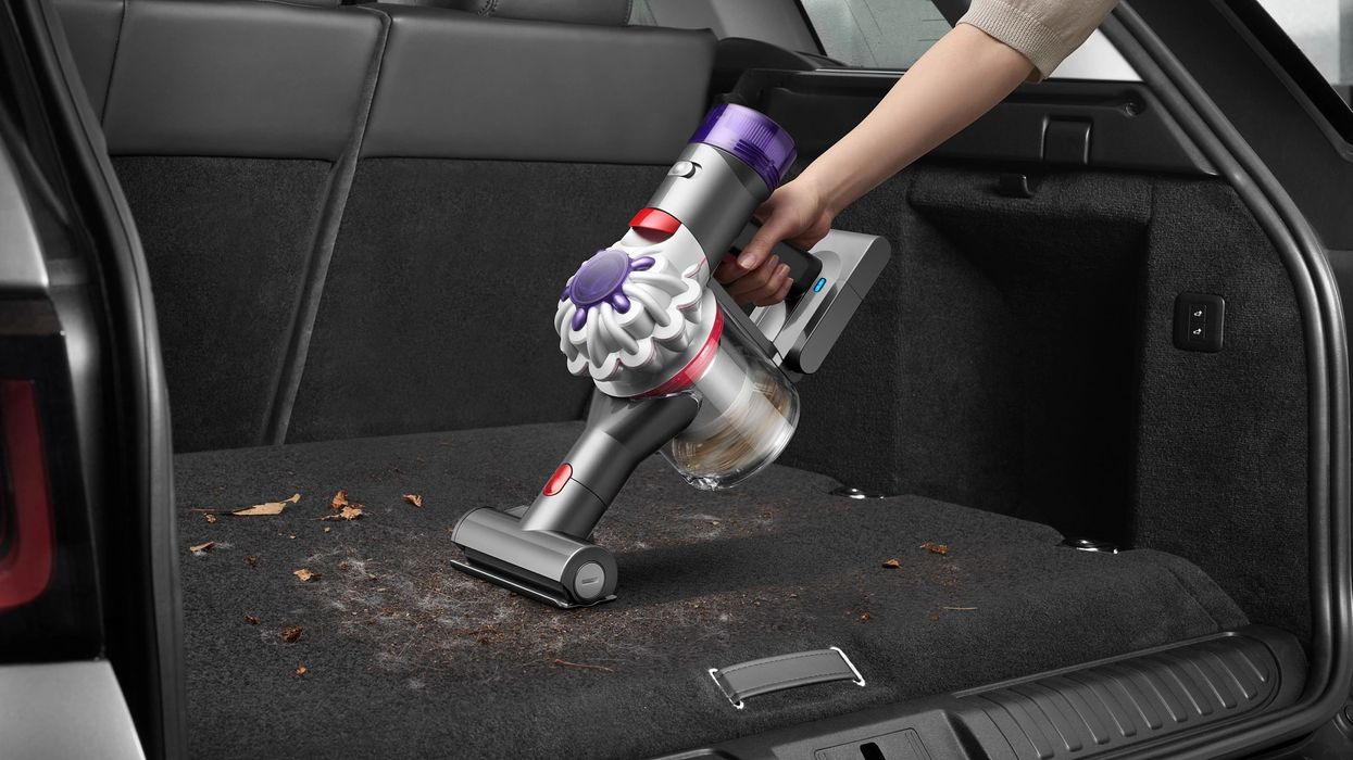 hand holding a dyson car + boat handheld being used in a car