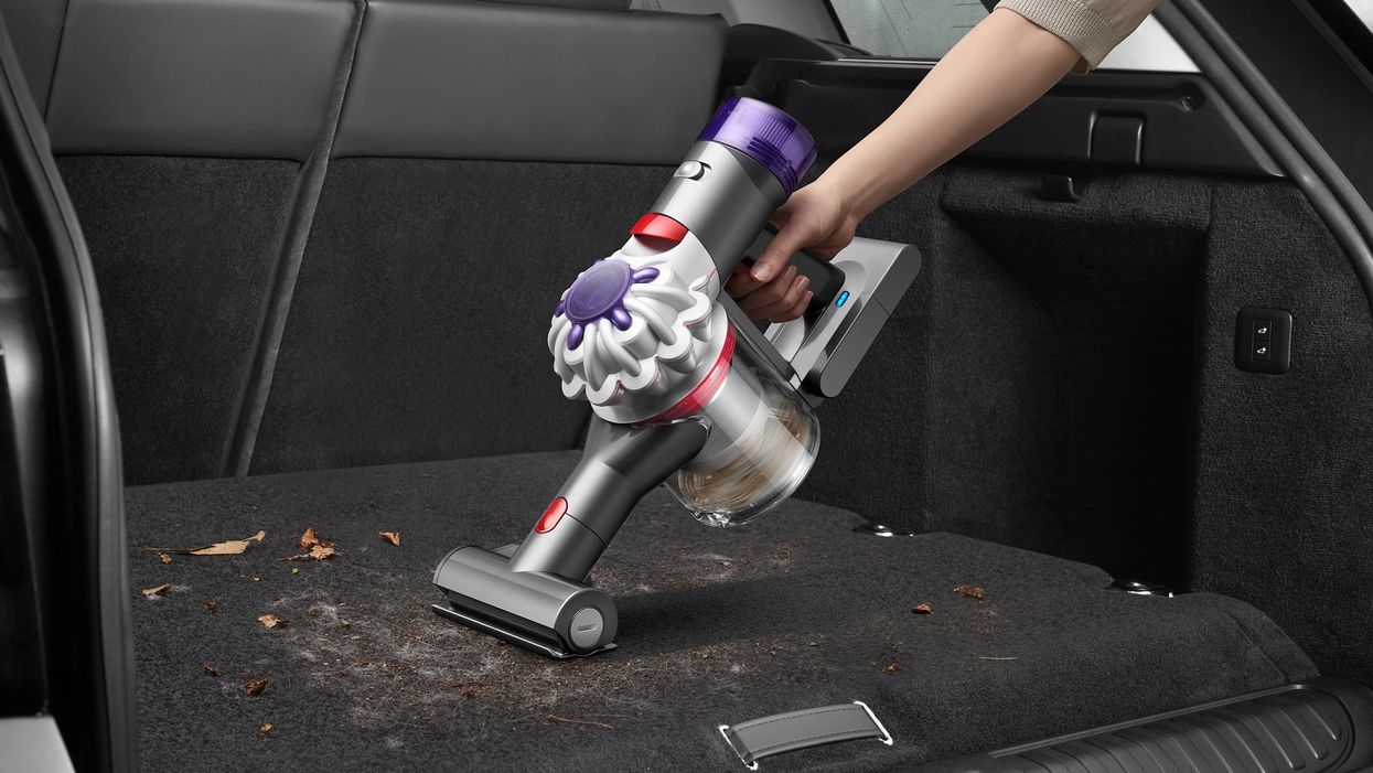 hand holding a dyson car + boat handheld being used in a car
