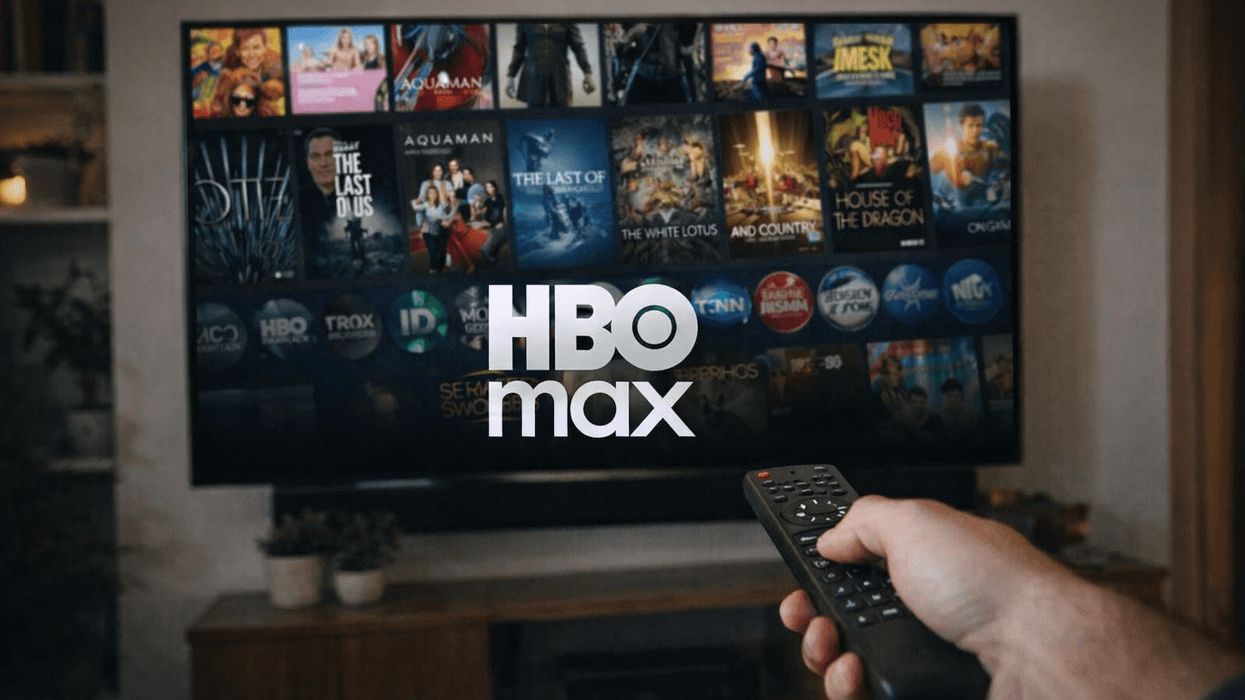 Hand holding a remote in front of TV screen displaying HBO Max logo