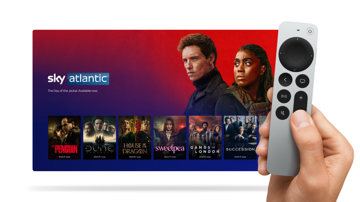 hand holding an apple tv remote control with a screen showing sky atlantic shows in the background