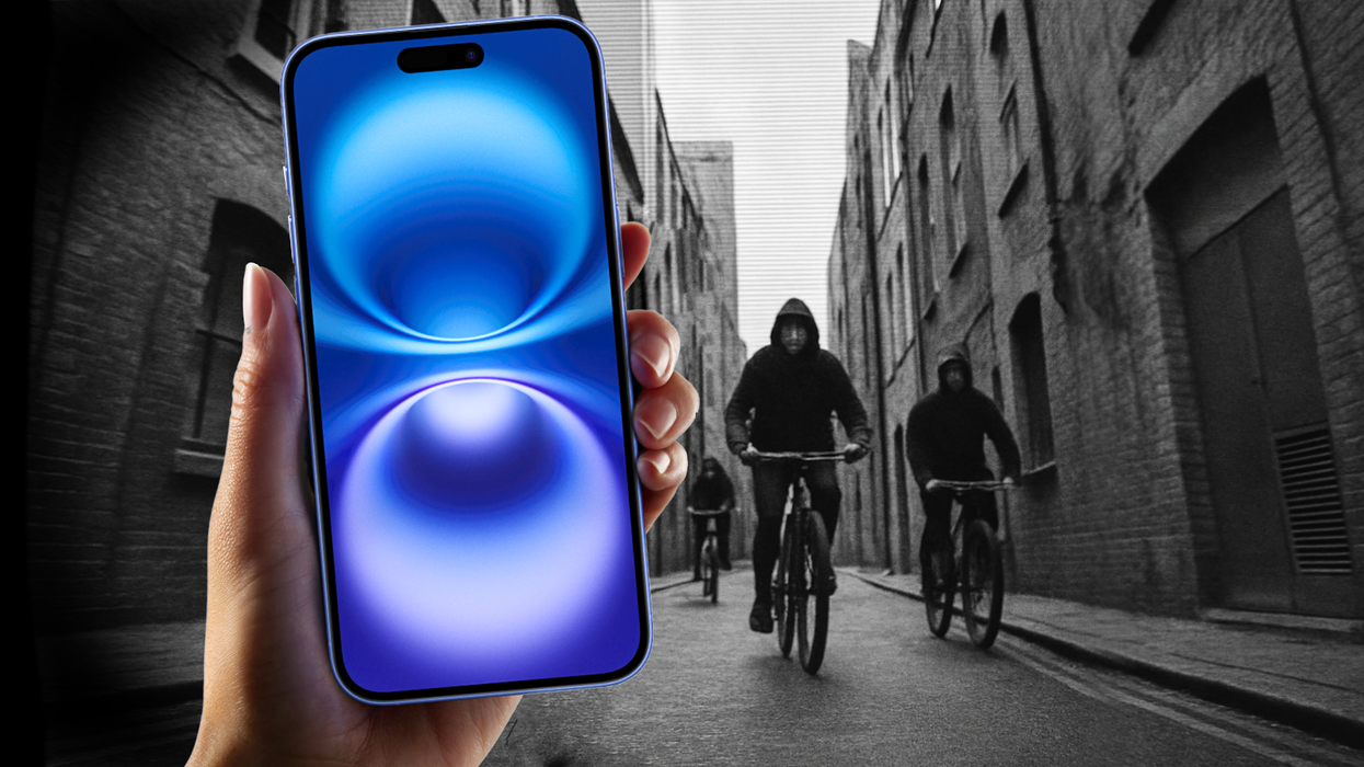 hand holding an iphone 16 with thieves on a bike in the background