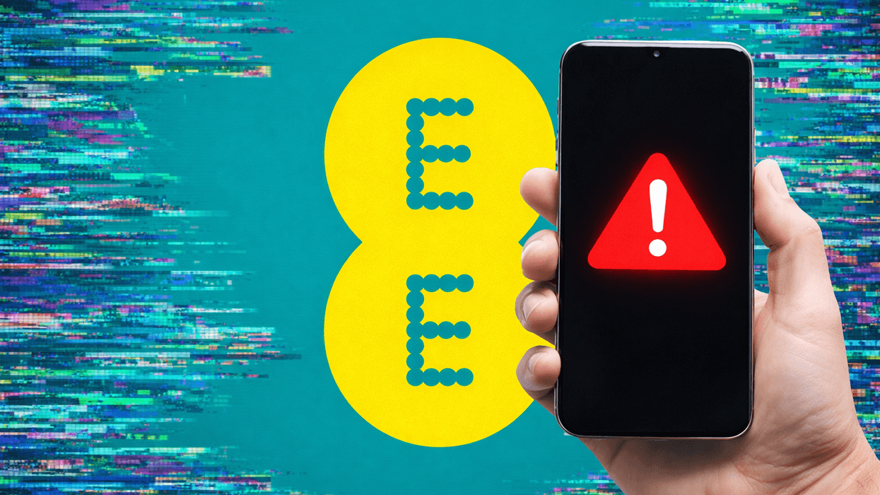 Hand holding mobile with warning symbol in front of EE logo