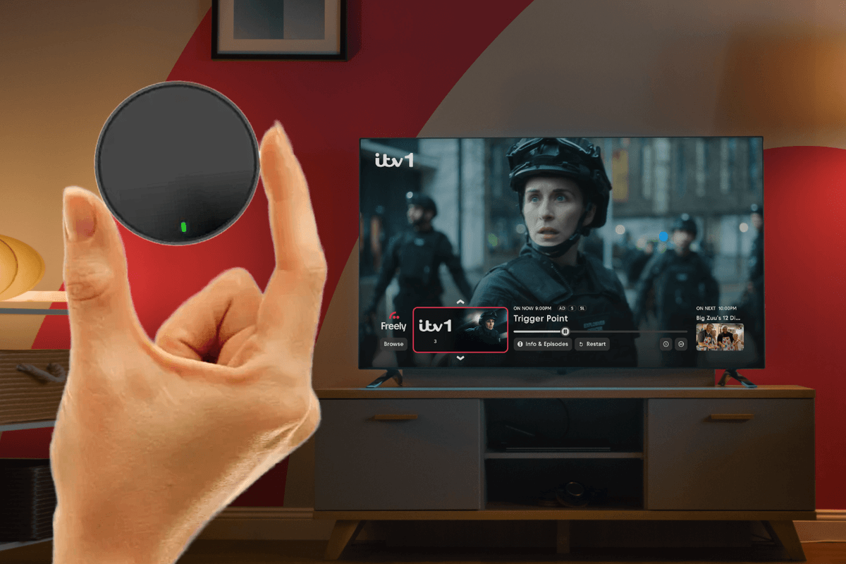 hand holding netgem pleio box with a television showing freely tv in the background