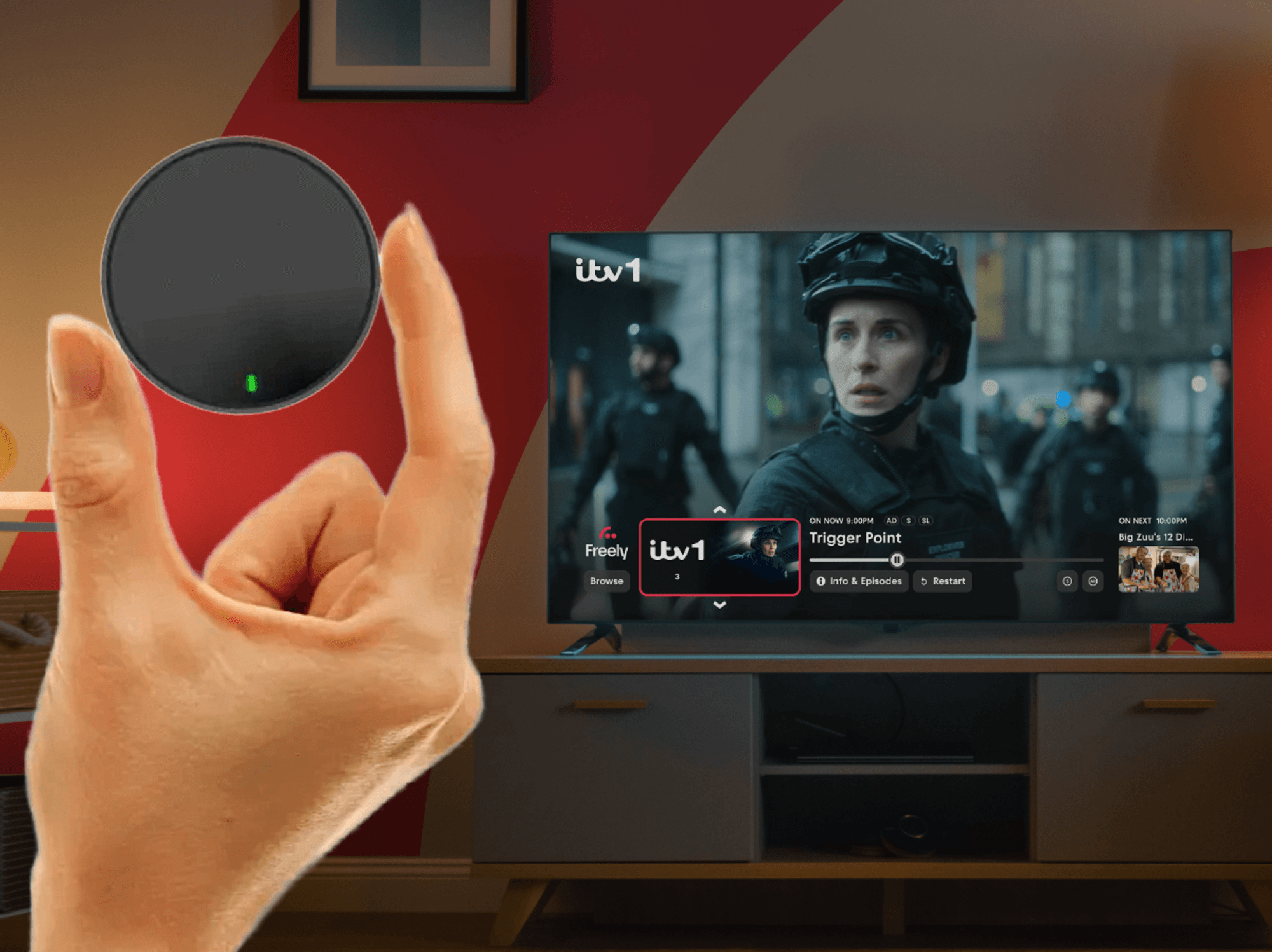 hand holding netgem pleio box with a television showing freely tv in the background