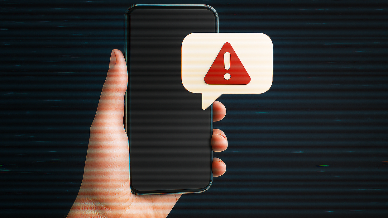 Hand holding phone with red alert symbol