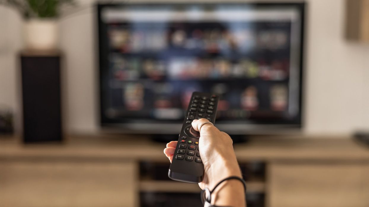 Hand holding remote in front of TV