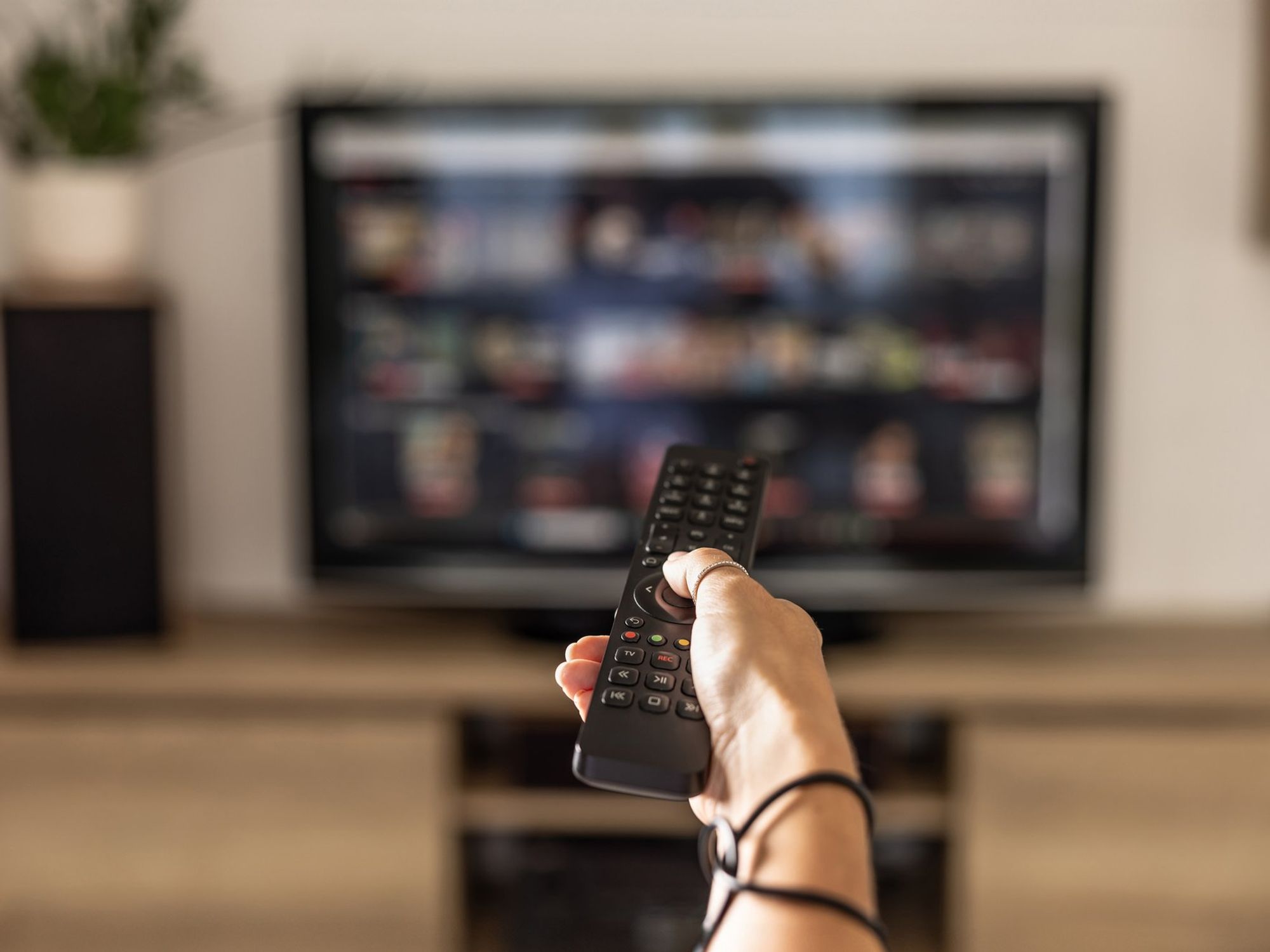 Hand holding remote in front of TV